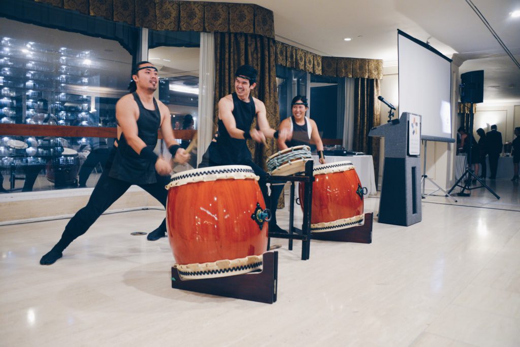 Drummers performing with standing drums at a local event.
