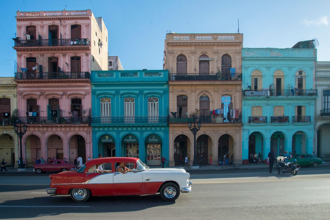 A car drives past colorful Cuban buildings