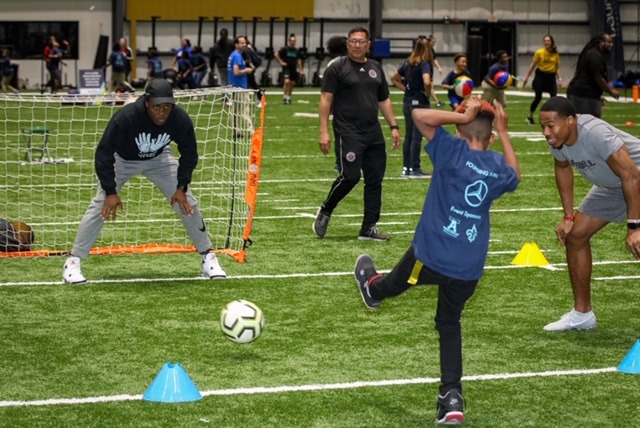 Boy kicks soccer into goals at Laureus training program
