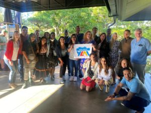 YLAI fellows and their hosts taking a group photo, holding a YLAI sign