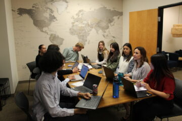 San Diego Diplomacy Council interns and employees gather around the conference table in their main office.