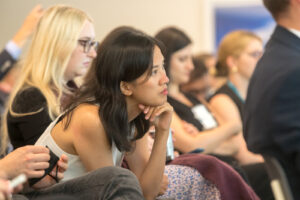 A young woman sits attentively at a presentation.